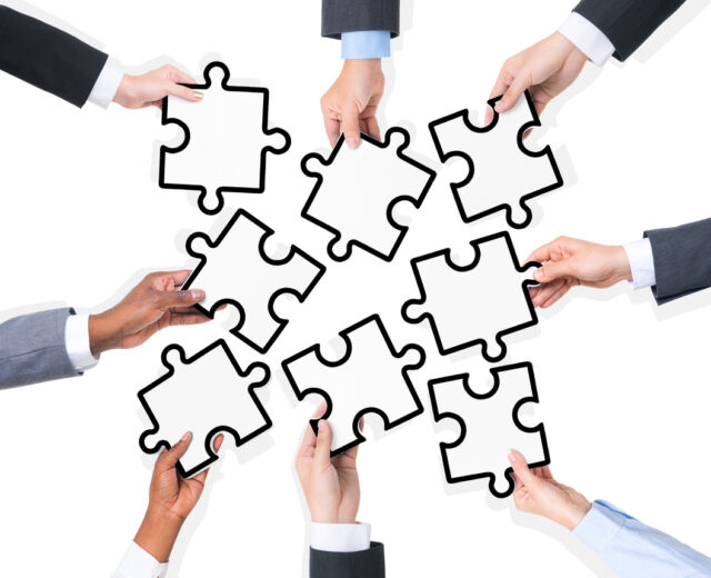 Group Of Business People Holding Pieces Of Puzzle